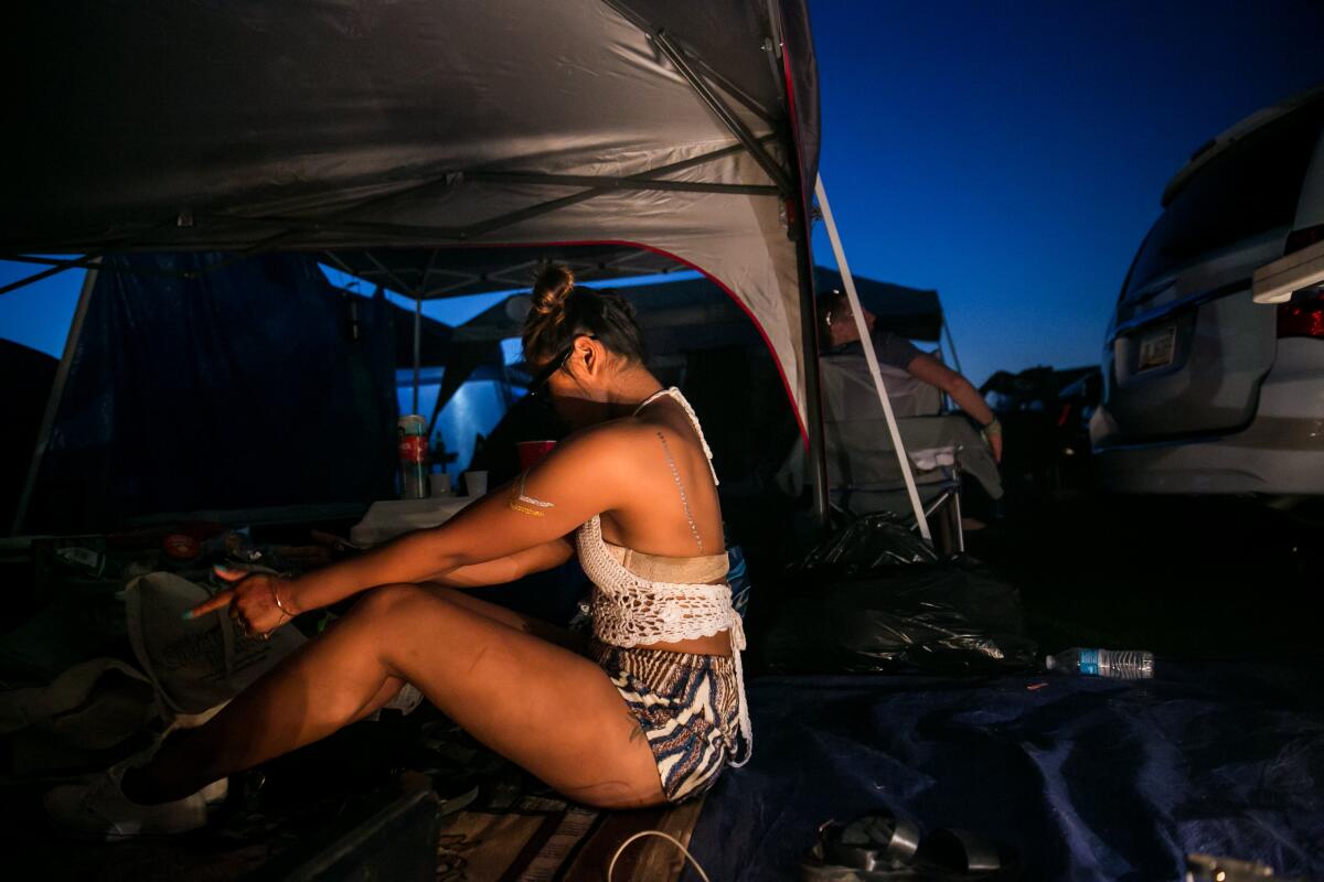 A festival-goer moves to music played at her tent during the Coachella Valley Music and Arts Festival at night.