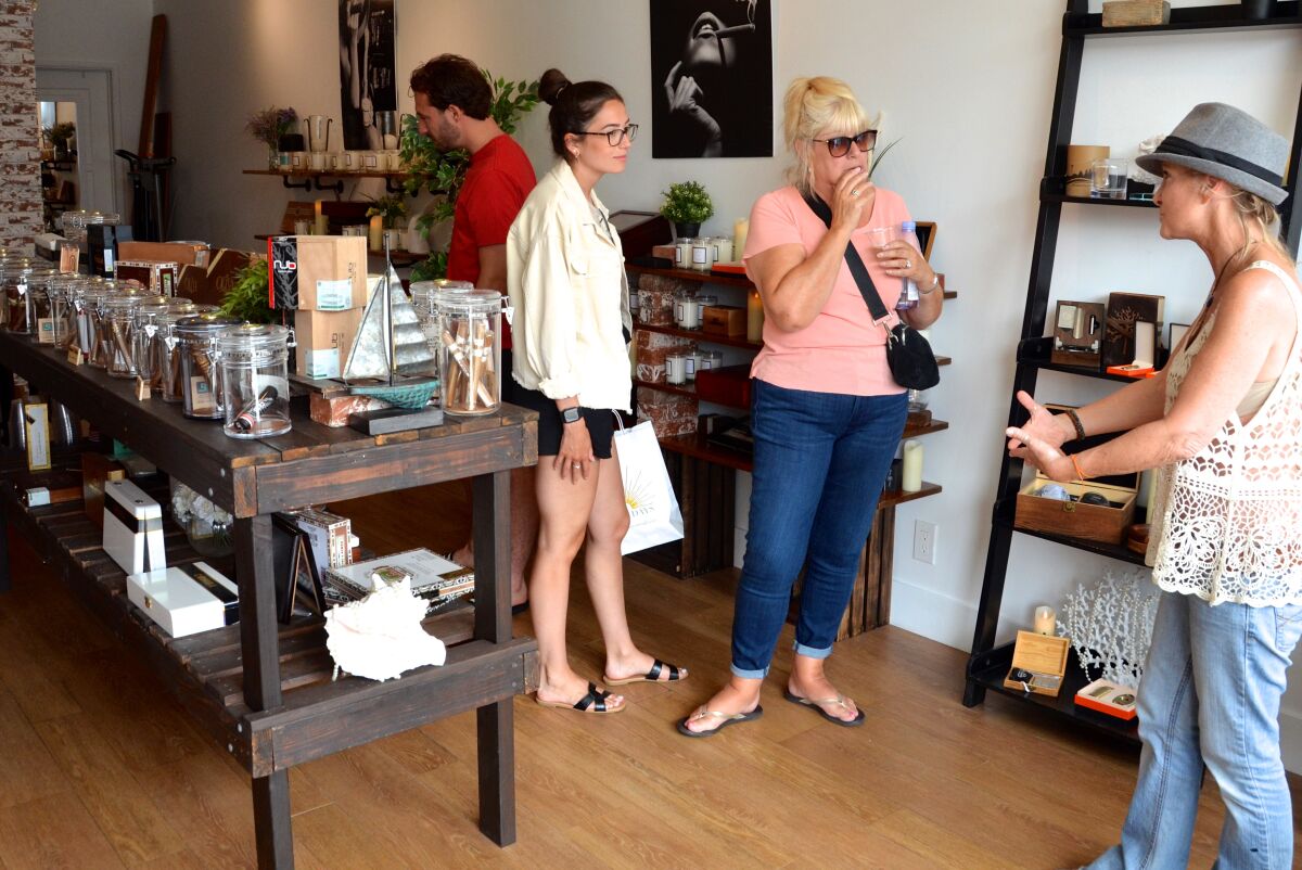 Sheryl Scarso, right, owner of J & S Makescents, helps customers Olivia Robinson, center and Lauren Robinson.