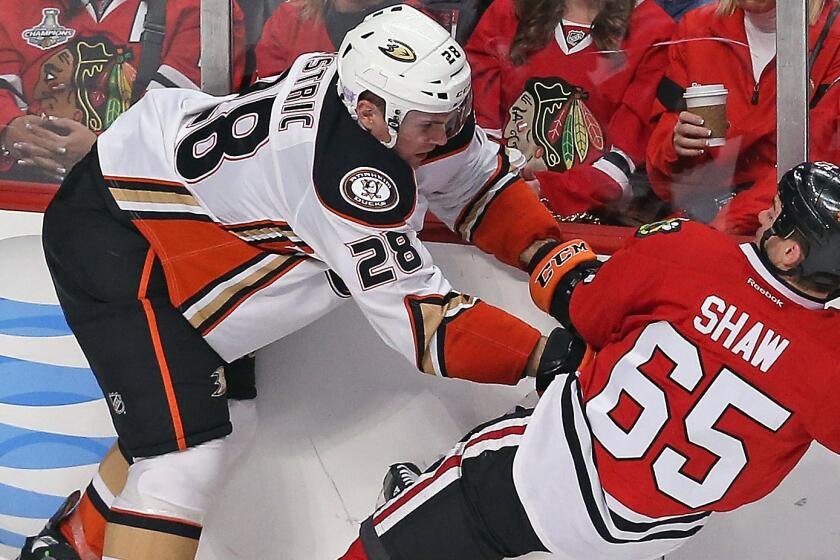 Ducks defenseman Mark Fistric, left, checks Chicago Blackhawks forward Andrew Shaw to the ice during a game on Oct. 28.