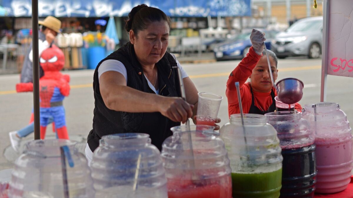 Angelica Rodriguez, left, and Merli Son serve up aguas frescas and other beverages from a street stand in the piñata district in downtown Los Angeles on March 23, 2019.