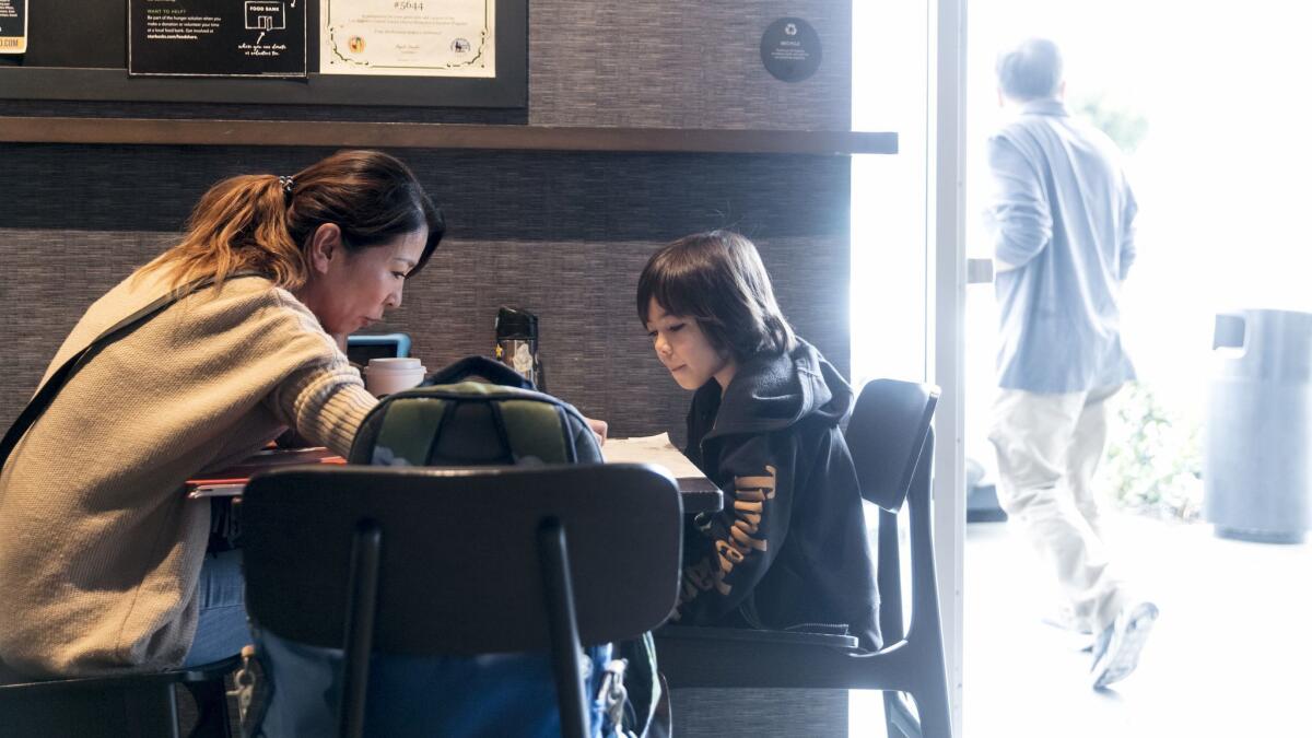 While members of United Teachers Los Angeles strike across the L.A. Unified School District, Mari Enyart, 42, helps her son Was Enyart, 7, with schoolwork while they spend their morning at a Starbucks in South Los Angeles.