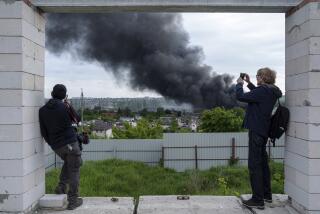 Periodistas extranjeros reportan desde un punto de observación, cerca de una columna de humo tras un ataque ruso, en Járkiv, Ucrania, el 17 de mayo de 2024. (AP Foto/Evgeniy Maloletka)