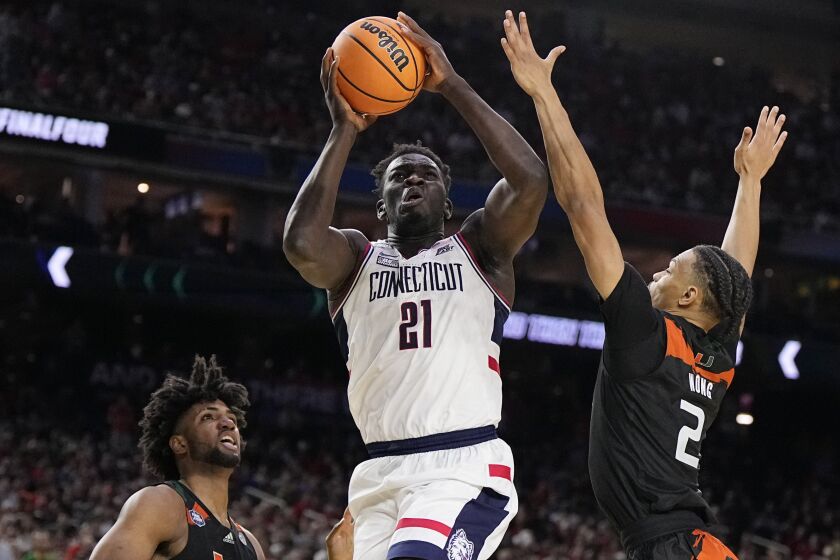 Connecticut forward Adama Sanogo scores past Miami guard Isaiah Wong during the second half of a Final Four college basketball game in the NCAA Tournament on Saturday, April 1, 2023, in Houston. (AP Photo/Brynn Anderson)
