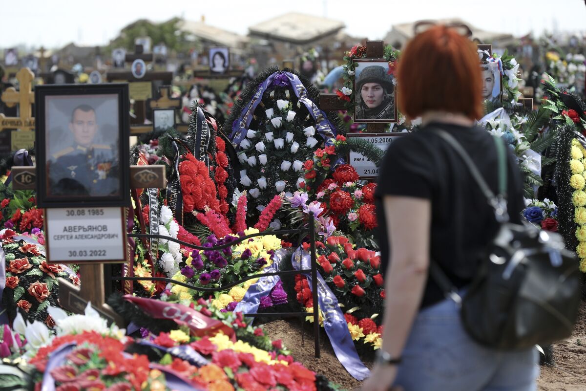 Woman at a Russian cemetery looking at graves of soldiers killed in Ukraine