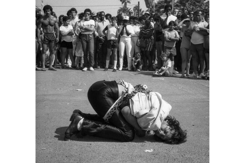 Escape artist Tim Eric performing in chains and straitjacket as crowd looks on in Venice Beach, Calif., 1984. Story appeared in the Los Angeles Times on July 8, 1984. Image from the Los Angeles Times Archive at UCLA.