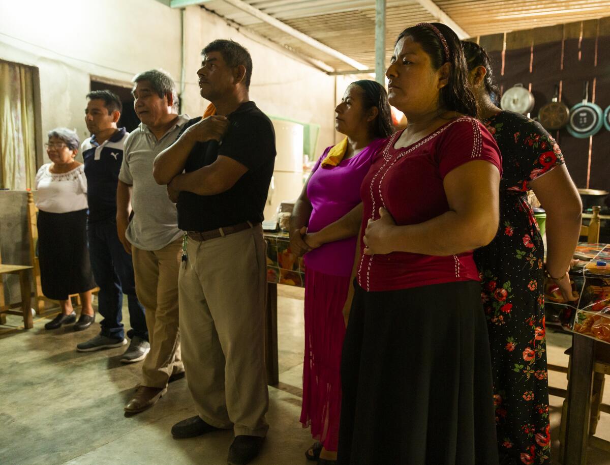 Members of the church congregation praying at the home of Maria Antonia Torres Morales. 