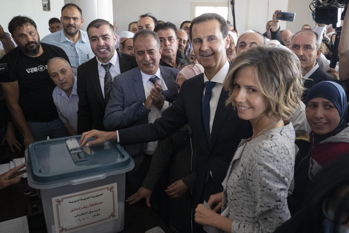 A grinning Bashar Assad casts his ballot surrounded by a crowd and his wife, Asma.