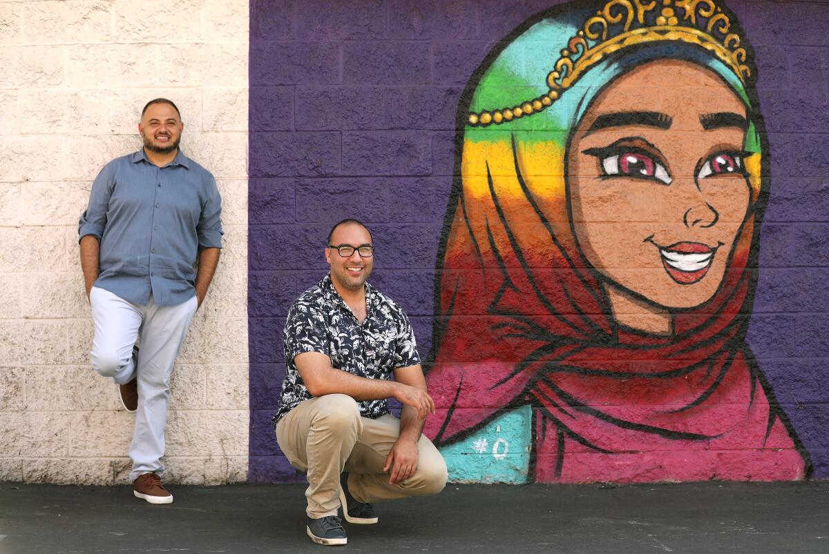 Executive director Rashad Al-Dabbagh and research fellow Amin Nash, are photographed with a "Hijabi Queens" mural.
