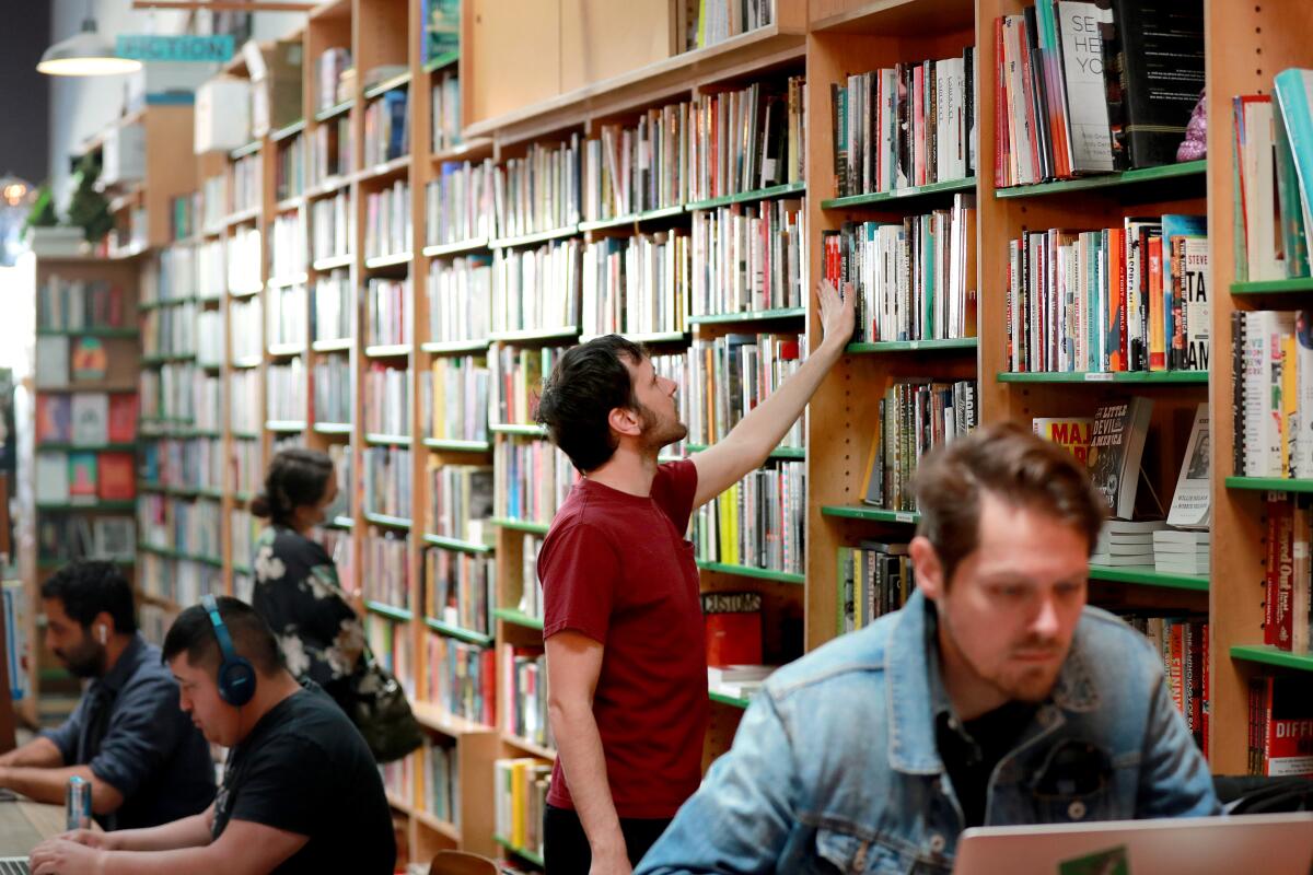 Gleb Wilson, center, views books at Stories Books and Cafe in Los Angeles in March 2022. 