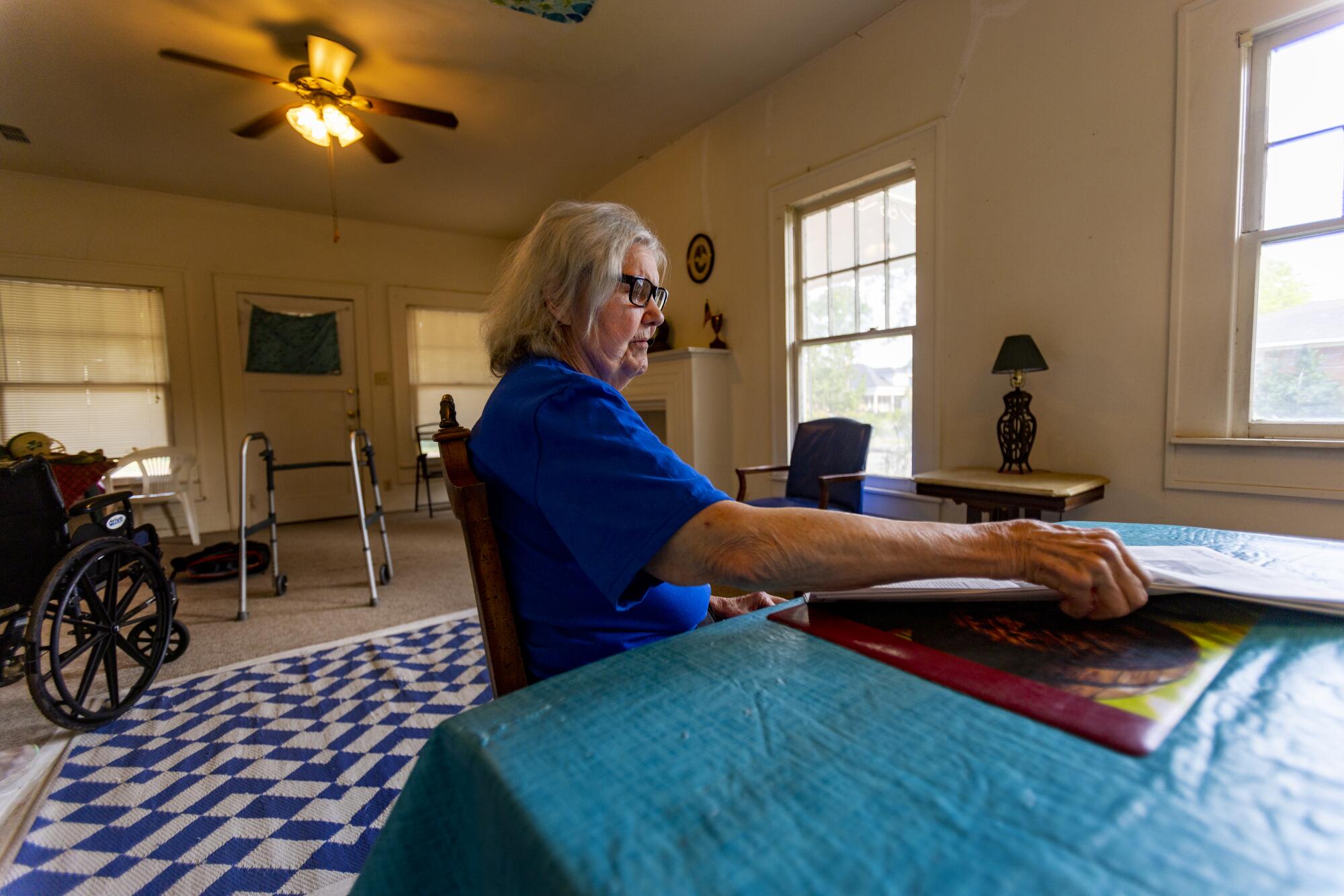 A woman sits at a table with a newspaper 