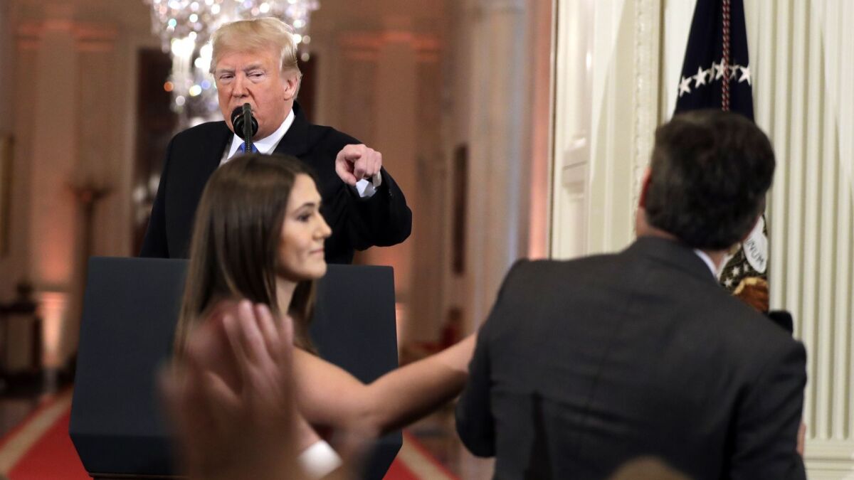 President Trump points to CNN reporter Jim Acosta during a Nov. 7 news conference as a White House aide reaches to take the microphone away from Acosta.