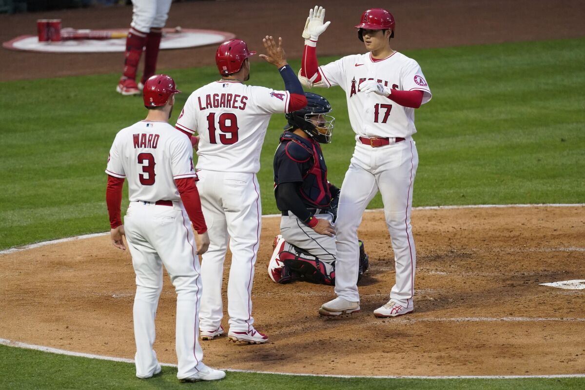 Los Angeles Angels designated hitter Shohei Ohtani (17) celebrates with Taylor Ward (3) and Juan Lagares (19) after hitting a home run during the second inning of a baseball game against the Cleveland Indians Monday, May 17, 2021, in Los Angeles. All three scored. (AP Photo/Ashley Landis)