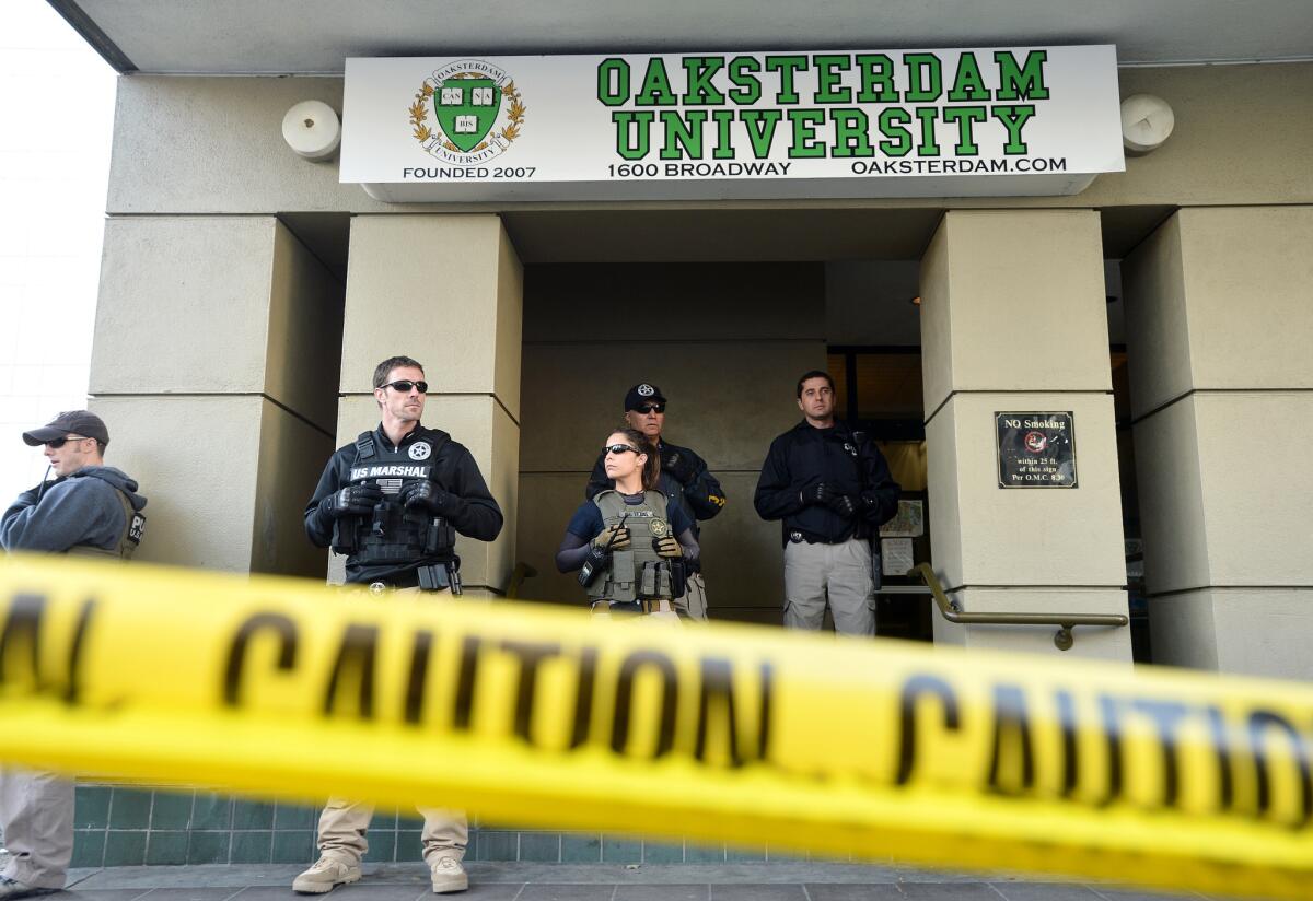 U.S. marshals stand at the entrance of Oaksterdam University in Oakland during a raid in 2012. The head of the university is pushing an initiative to legalize recreational use of marijuana for adults.