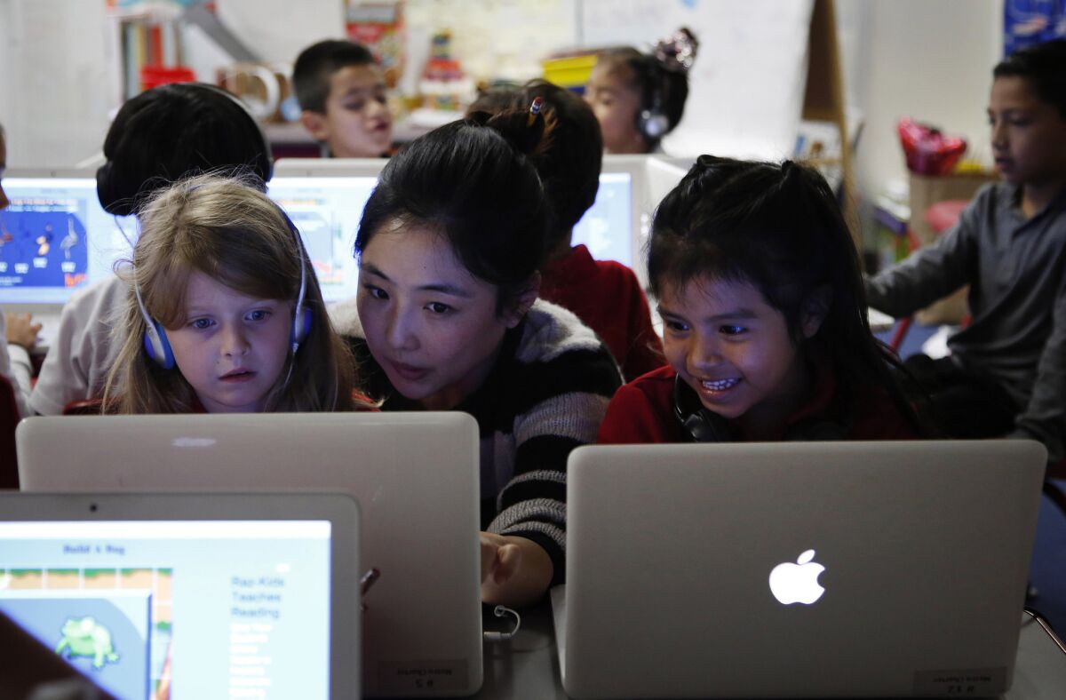 Teacher Michelle Lee, center, works with Audrey Eckert, 6, left, and Jaqueline Hernandez, 5, at Metro Charter Elementary in downtown Los Angeles in June.