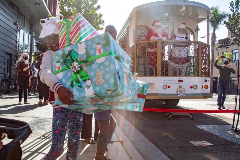 SAN DIEGO, CA - DECEMBER 10: Imani, 7, was excited to receive presents from Mr. and Mrs. Claus outside Father JoeOs Villages on Thursday, Dec. 10, 2020 in San Diego, CA. (Jarrod Valliere / The San Diego Union-Tribune)