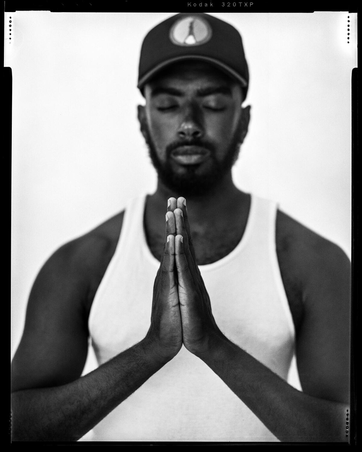 Black and white film photo of a Black man, Etienne Maurice, holding a yoga pose