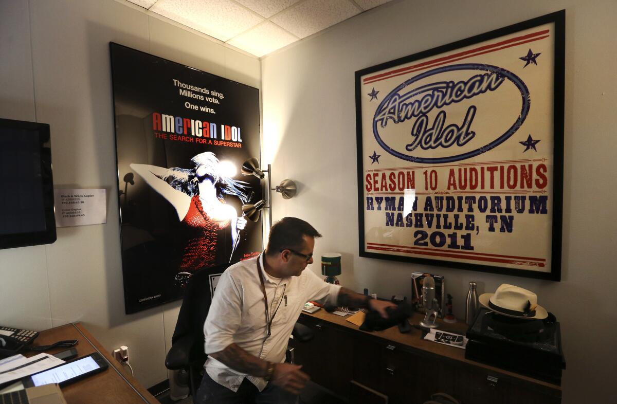 Patrick Lynn Sr., supervising producer for "American Idol," works in his office at CBS Television City in Hollywood. On his wall are rare posters promoting the show from Season 1, left, and Season 10.