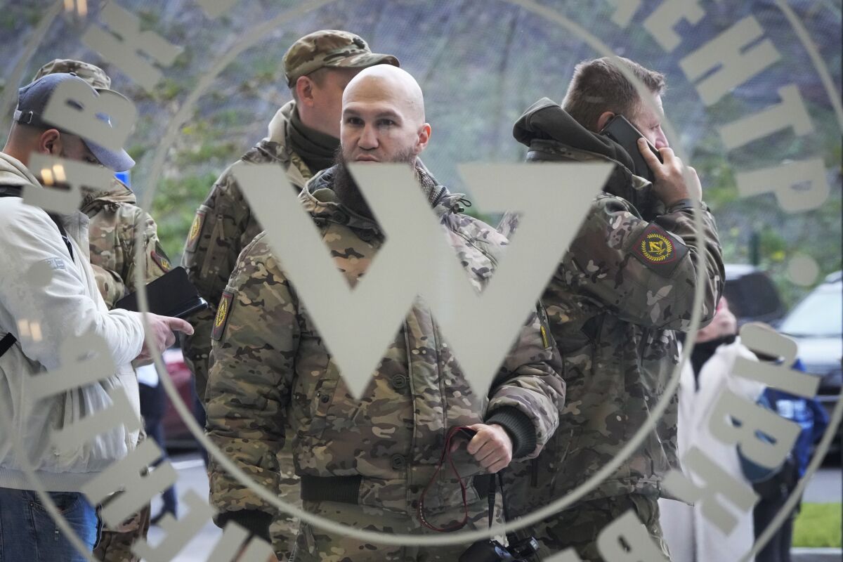 Visitors wearing military camouflage are seen through a glass entrance bearing a white round logo with the letter W