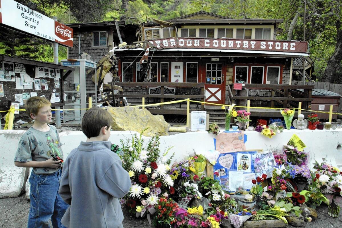 Lukas Teissere, left, and Danny Johnson, both of Silverado Canyon, view the makeshift memorial for Caitlin Oto at the Shadybrook Country Store in Silverado Canyon in 2005. On Feb. 20 of that year, boulders crashed down killing Oto, 16, who was in her room.