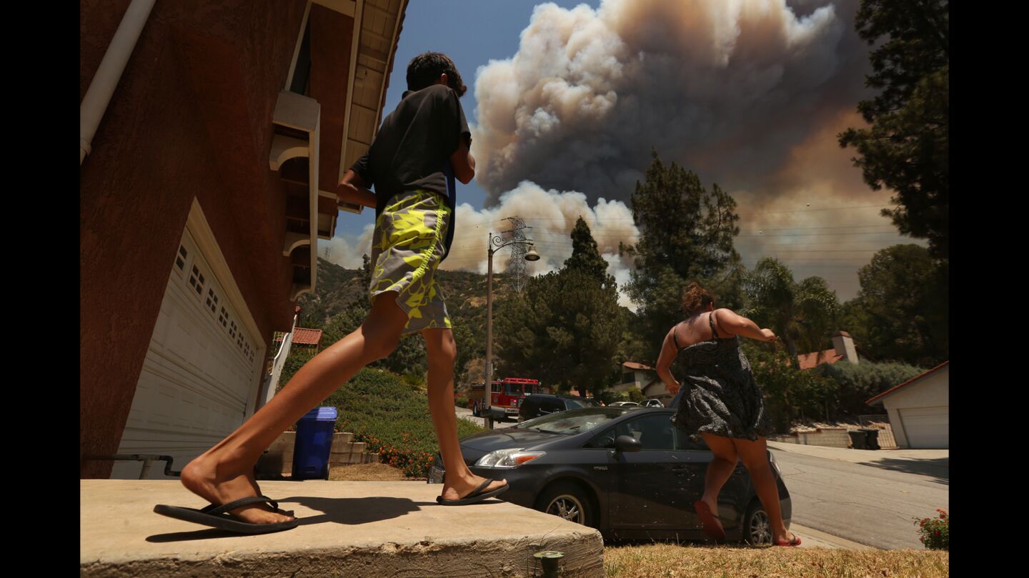 Sebastian Guzman, 11, and Samantha Karakashyan, 12, evacuate a home on Las Lomas Road as a wildfire that started in Duarte heads in their direction.