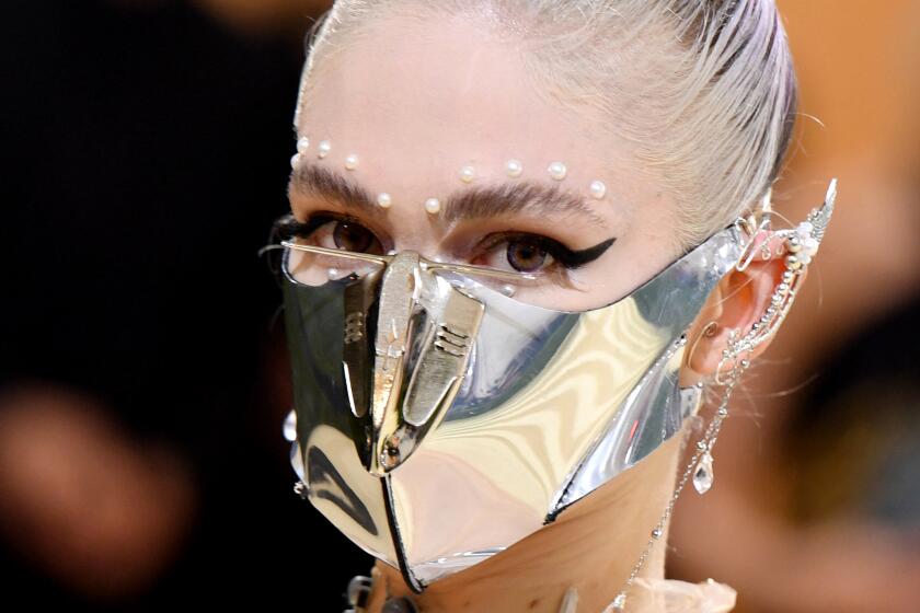 Singer-songwriter Grimes arrives for a gala wearing a metallic silver mask and jeweled elf ears
