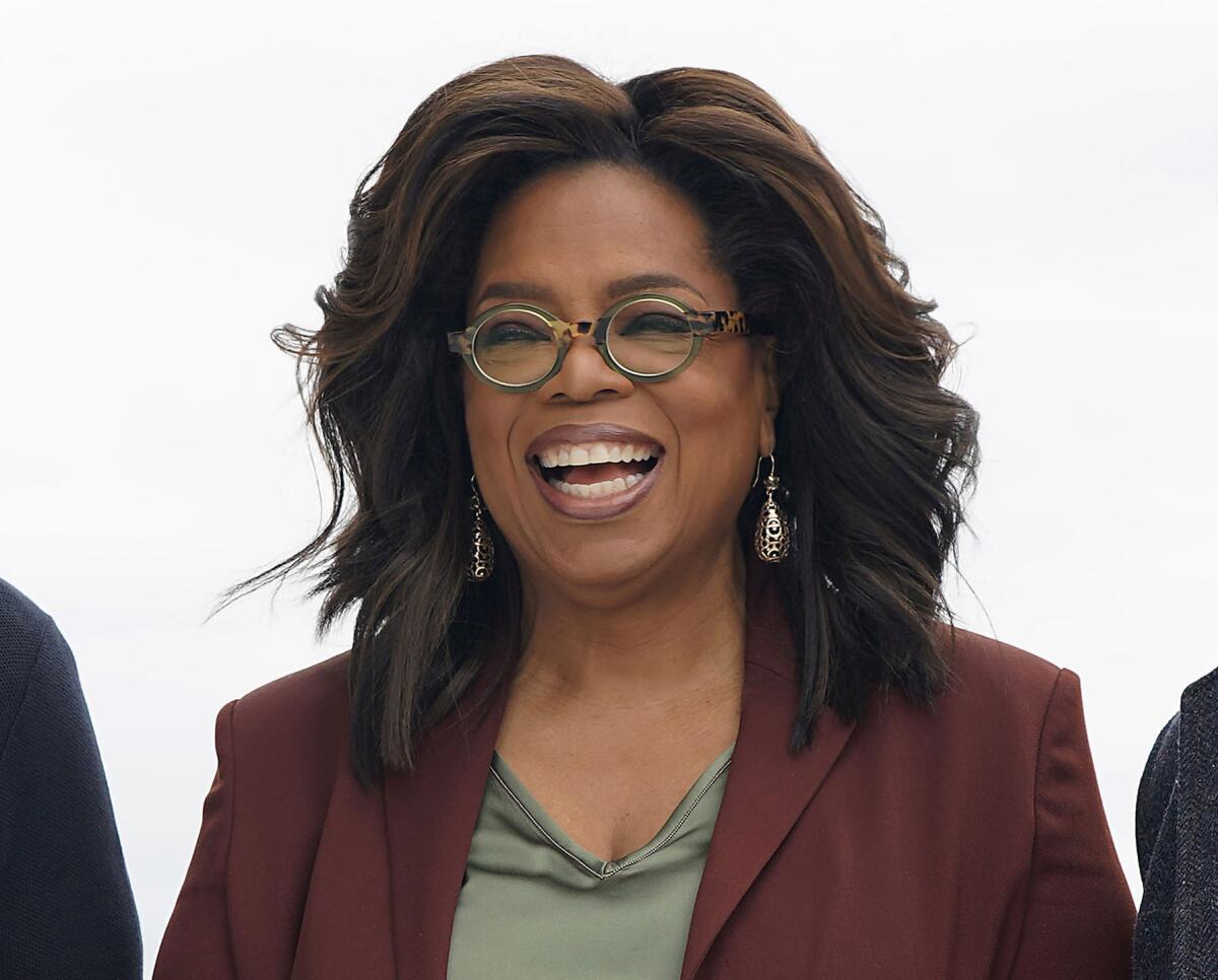 A woman in a suit jacket and glasses flashes a broad smile