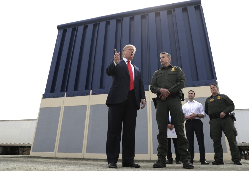FILE - In this March 13, 2018, file photo, President Donald Trump speaks during as he reviews border wall prototypes, in San Diego, as Rodney Scott, the Border Patrol's San Diego sector chief, listens. The Trump administration has named Rodney Scott the new head of the U.S. Border Patrol. Scott will take over for Carla Provost, who is retiring, according to an announcement obtained Friday by The Associated Press from Mark Morgan, acting head of U.S. Customs and Border Protection. Scott has been a member of the Border Patrol for 27 years. (AP Photo/Evan Vucci, File)
