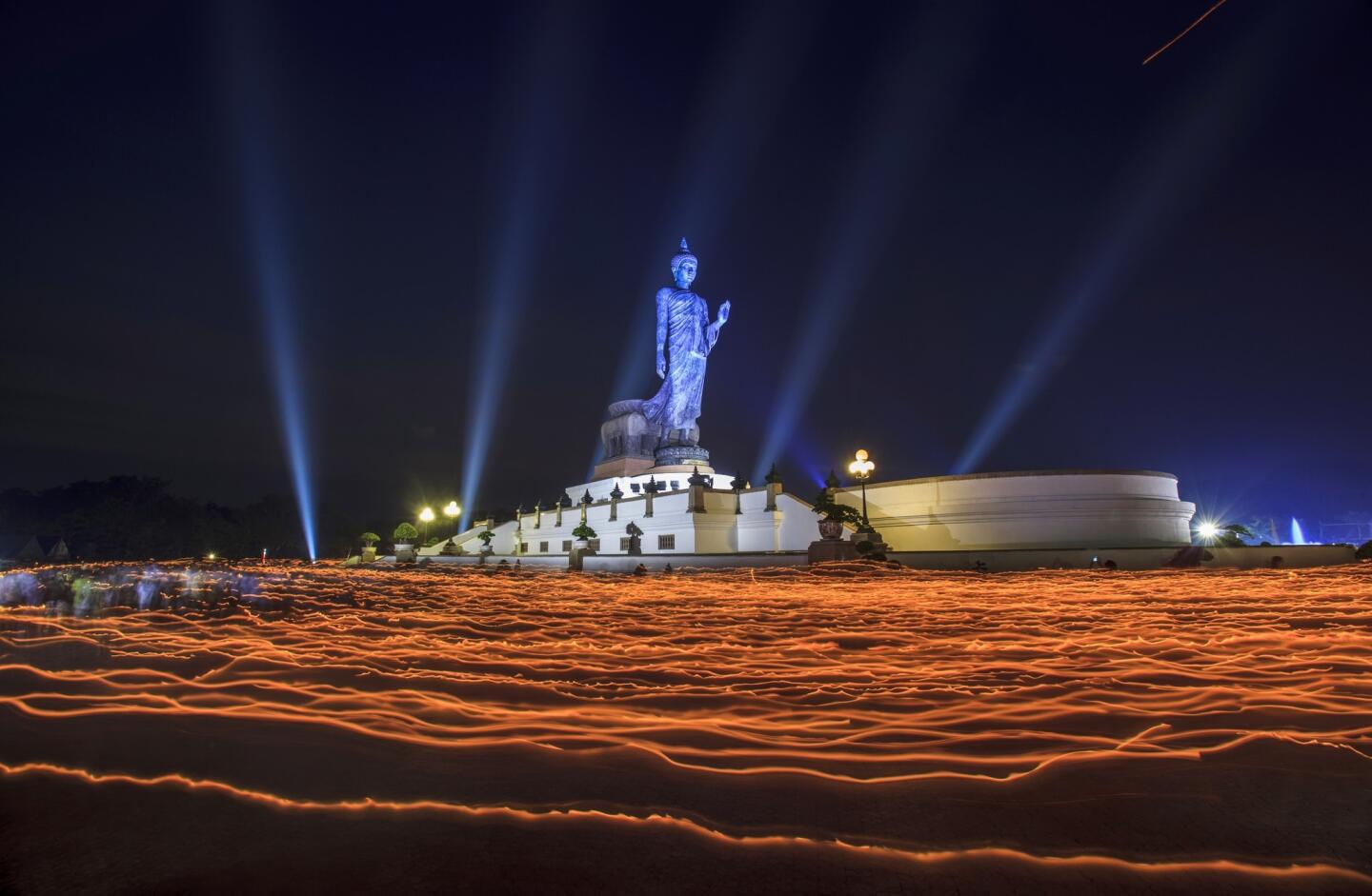 People walk around the Buddha statue holding candles for prayers during Makha Bucha Day at Buddhist Park on Feb. 25, 2013, in Nakhon Pathom, Thailand.