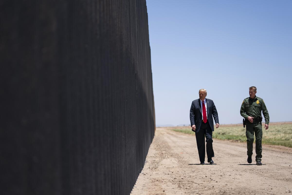 Border Patrol chief Rodney Scott and Donald Trump walk along a wall