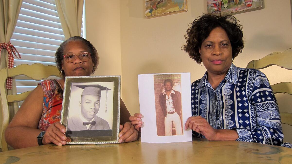 Mylinda Byrd Washington, 66, left, and Louvon Byrd Harris, 61, hold up photographs of their brother James Byrd Jr. in Houston.
