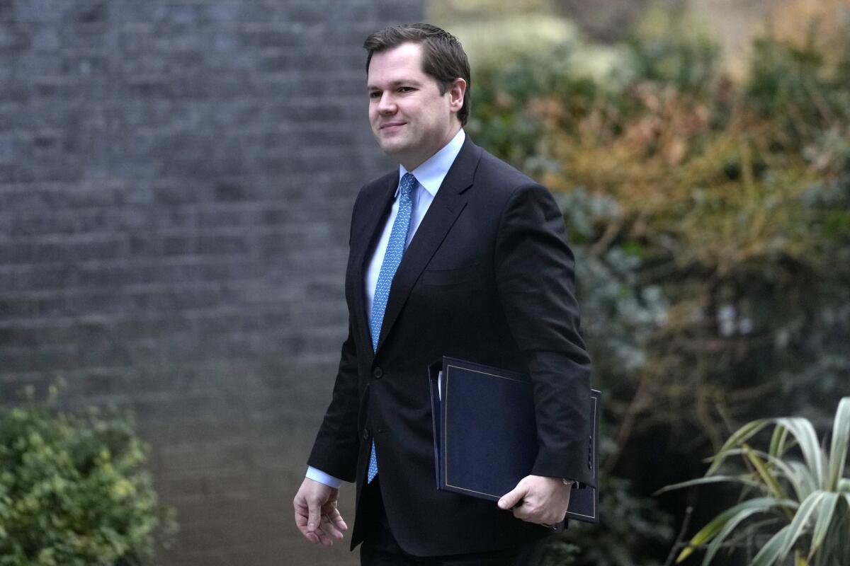 A man in a suit walks by a brick wall.