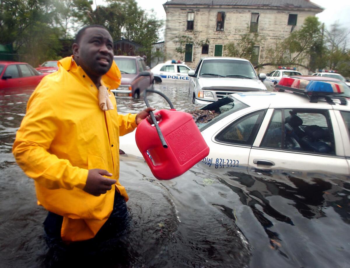 New Orleans Police Officer N. Daggs wades through the streets to siphon gas to fuel generators at Bywater Hospital, where many patients could not be safely moved. (Matt Rourke / Associated Press)