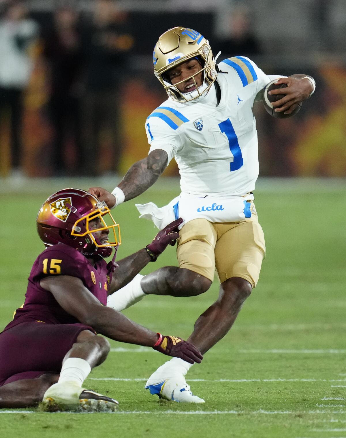 UCLA quarterback Dorian Thompson-Robinson (1) gets stopped by Arizona State defensive back Khoury Bethley (15) during the second half of an NCAA college football game in Tempe, Ariz., Saturday, Nov. 5, 2022. UCLA won 50-36. (AP Photo/Ross D. Franklin)