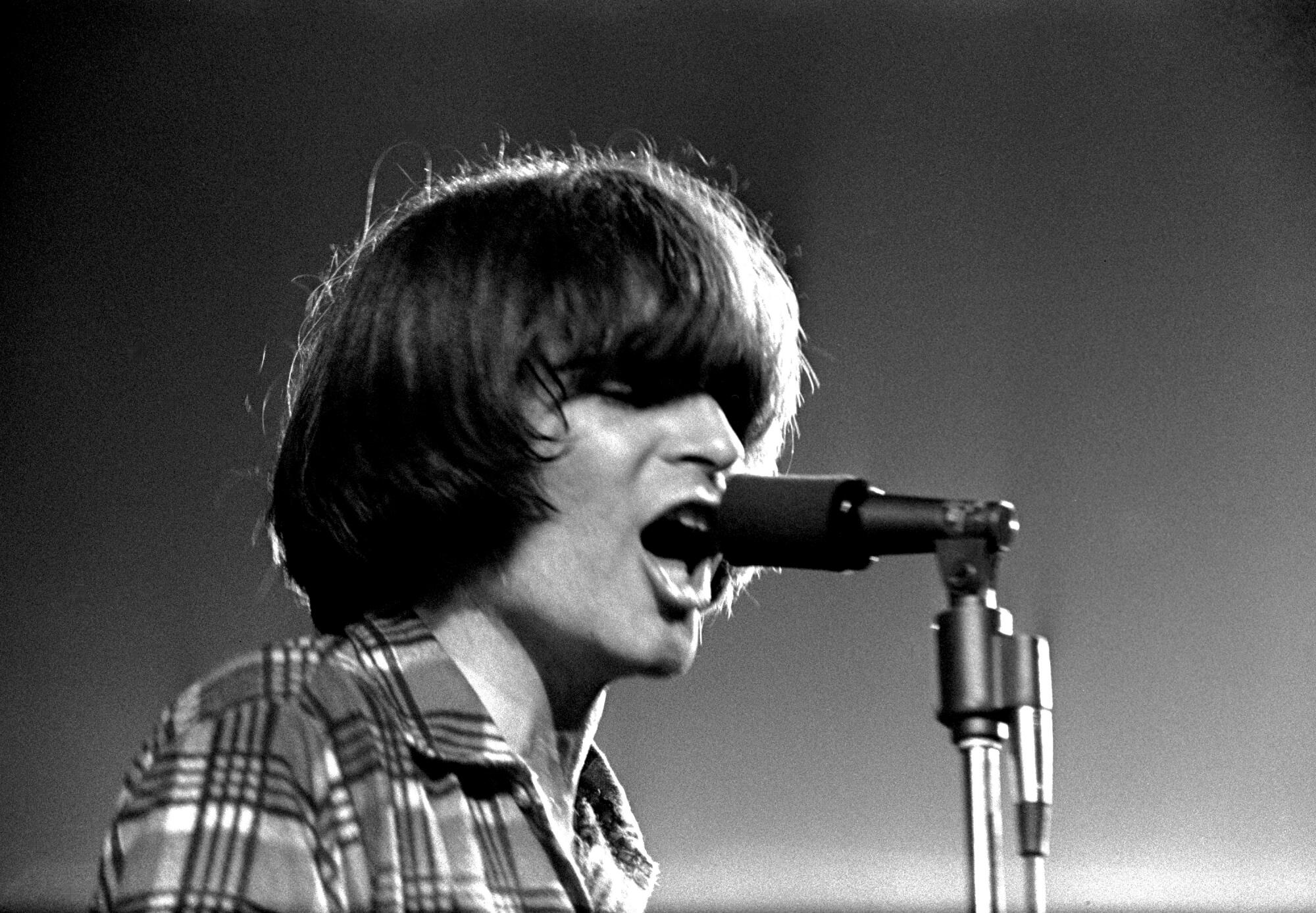 A rock singer in a flannel shirt performing onstage in 1970
