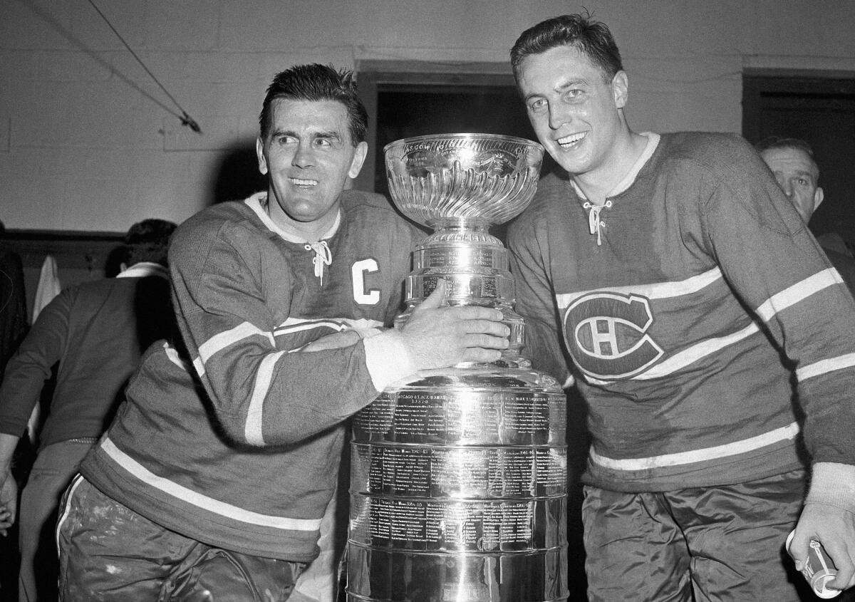 Maurice Richard, left, and Jean Beliveau stand on either side of the Stanley Cup after the Montreal Canadiens' victory over the Boston Bruins in 1958.
