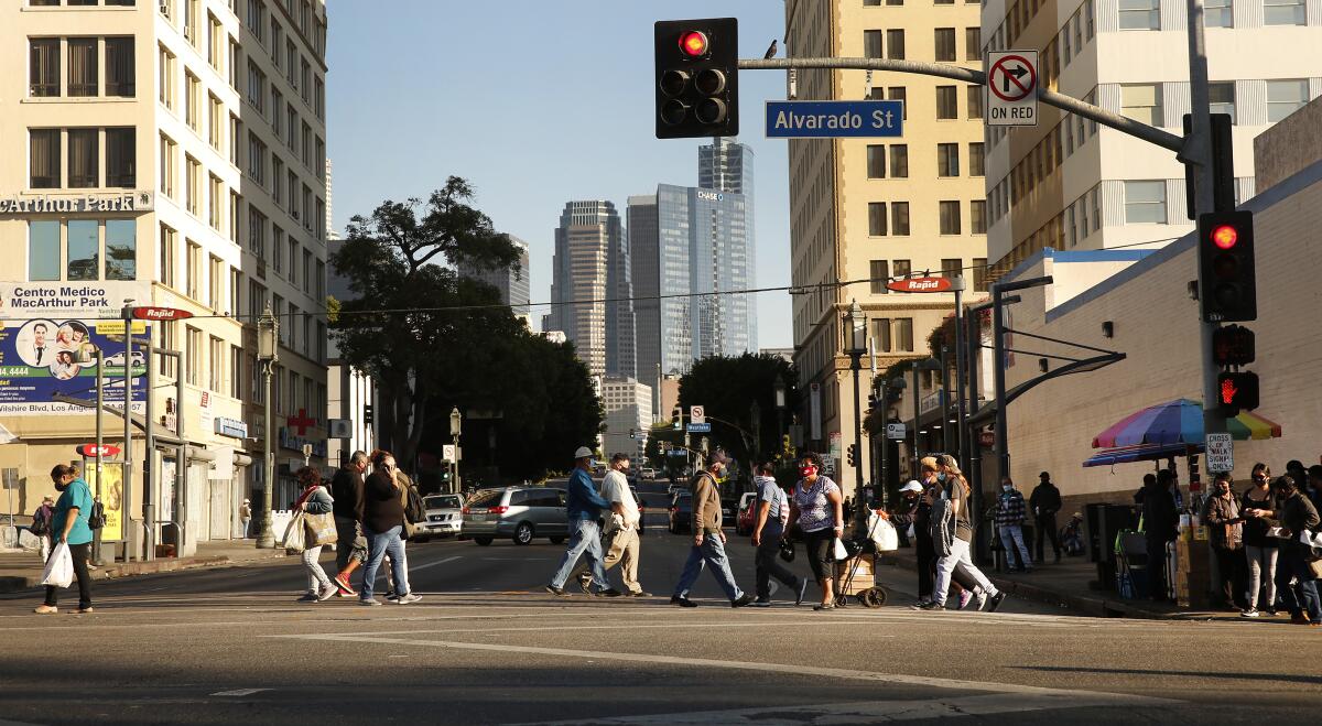 People cross a city street with skyscrapers in the background