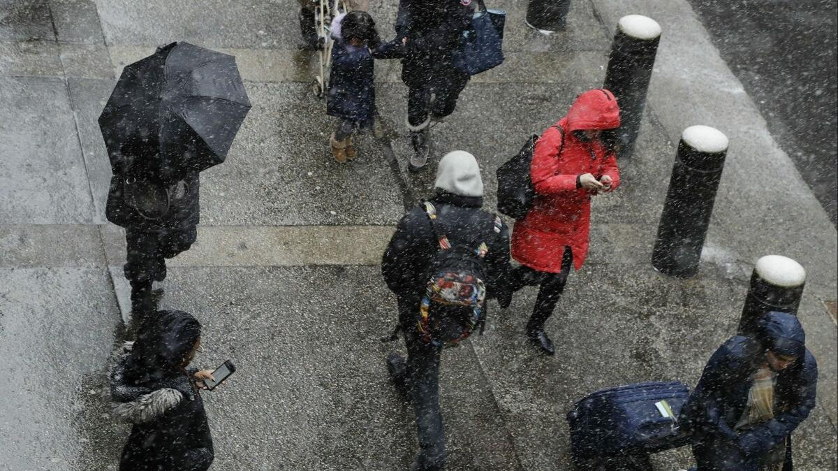 Pedestrians walk along 42nd Street as snow falls in New York City on Wednesday.