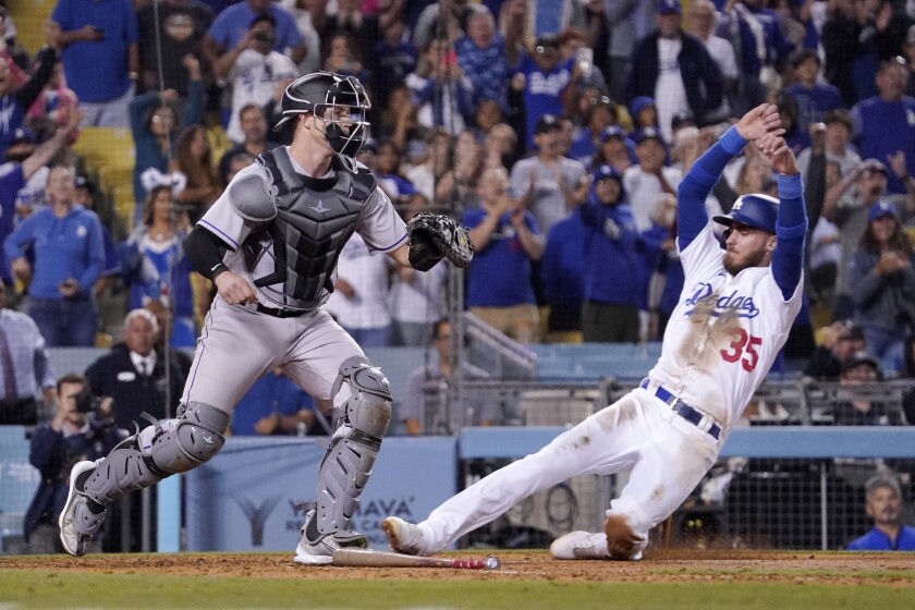 Los Angeles Dodgers' Cody Bellinger, right, scores the winning run on a single by Mookie Betts as Colorado Rockies catcher Brian Serven waits for the ball during the ninth inning of a baseball game Wednesday, July 6, 2022, in Los Angeles. (AP Photo/Mark J. Terrill)
