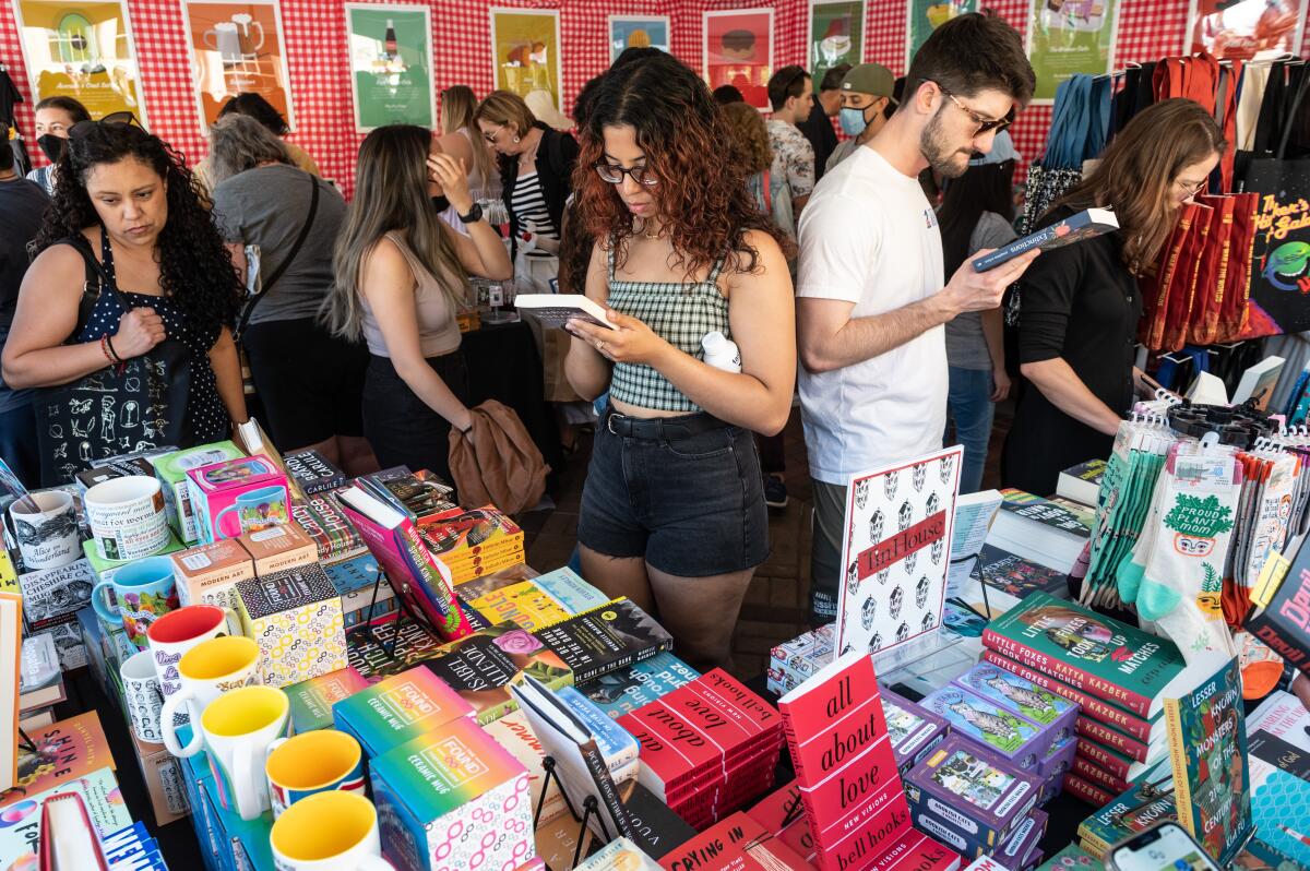A woman and a man look at books in a crowded festival stall. 