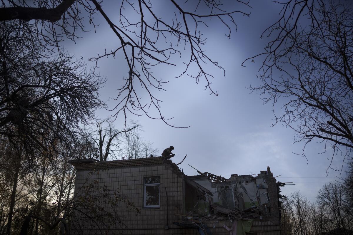 A soldier is silhouetted on a destroyed Ukrainian building.