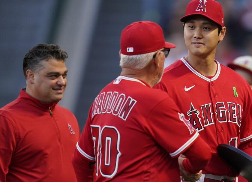Shohei Ohtani shakes hands with manager Joe Maddon. Angels general manager Perry Minasian is at left.