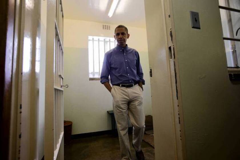 President Obama walks from Nelson Mandela's cell during a tour on Robben Island, South Africa.