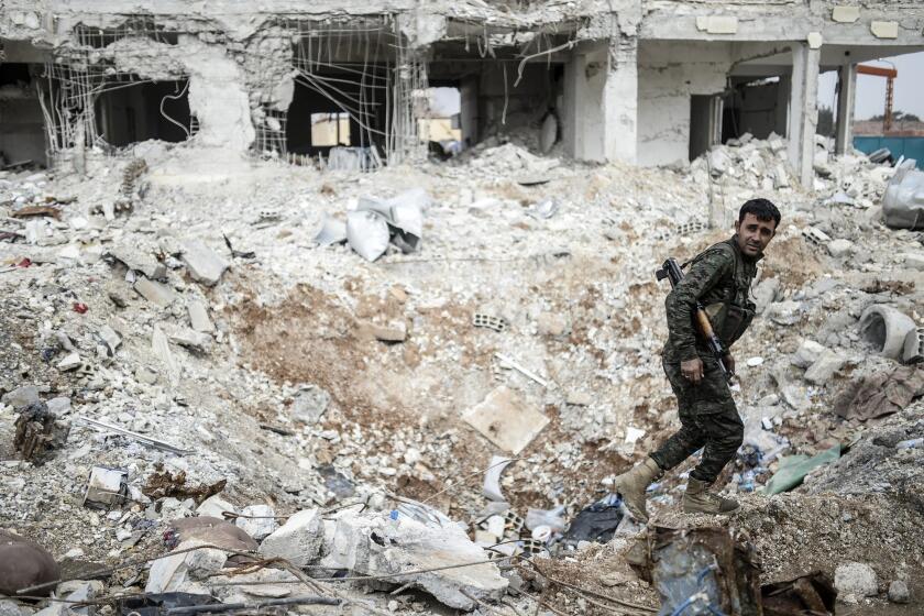 A Kurdish fighter walks through the wreckage of a building in the center of Kobani, Syria, on Jan. 28.