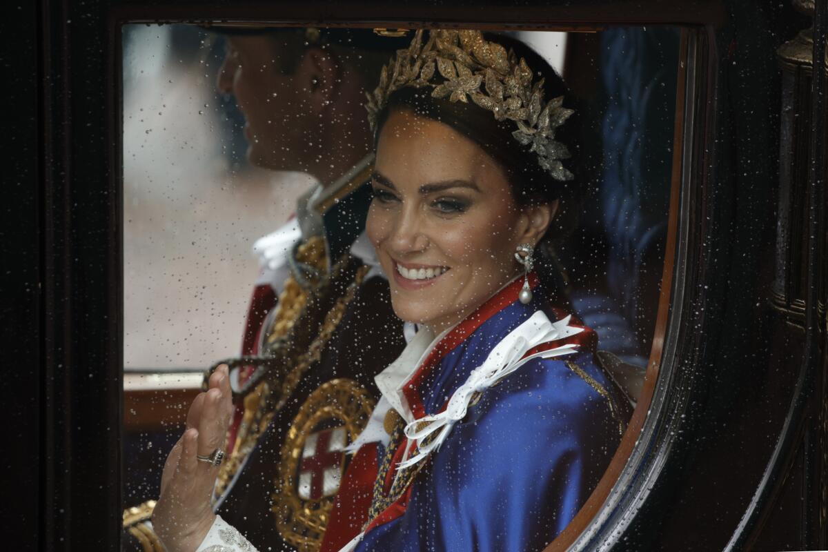 Princess Catherine in royal finery waving from inside a royal carriage