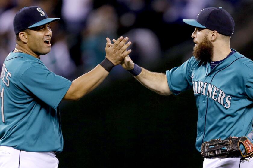 Mariners teammates Kendrys Morales, left, and Dustin Ackley celebrate after their 4-3 victory over the Angels on Friday night in Seattle.
