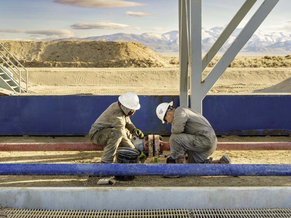 Two workers fit a pipe at Fervo Energy's Project Red site in northern Nevada.