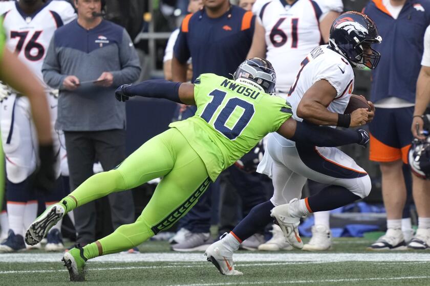 Denver Broncos quarterback Russell Wilson, right, is sacked by Seattle Seahawks linebacker Uchenna Nwosu (10) during the first half of an NFL football game, Monday, Sept. 12, 2022, in Seattle. (AP Photo/Stephen Brashear)