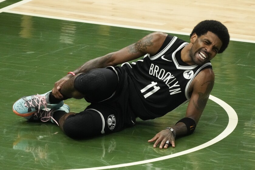 Brooklyn Nets star Kyrie Irving holds his leg after sustaining an injury in the Milwaukee Bucks' victory.