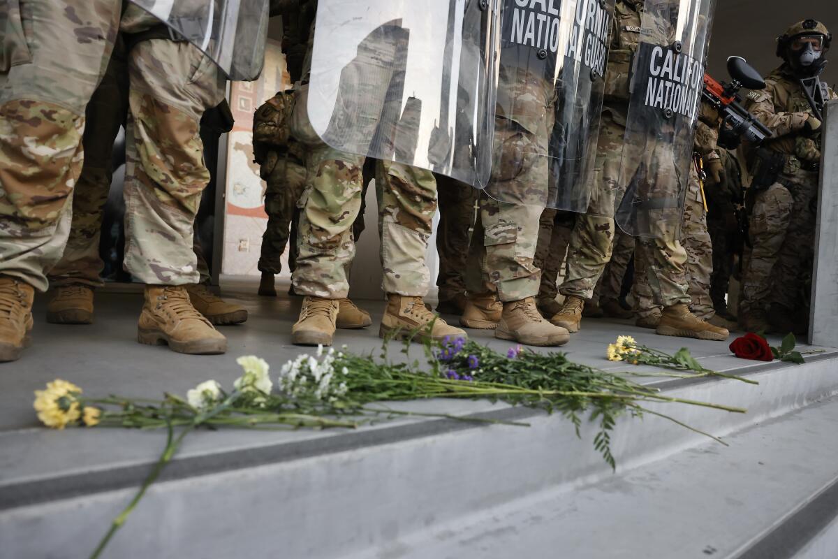 Flowers lay at the feet of federalized California National Guard members.