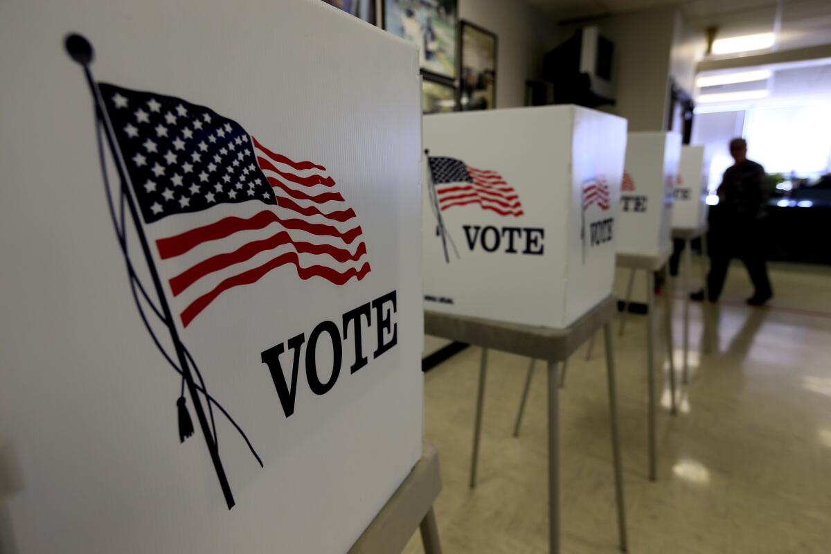 White voting booths with the U.S. flag and the word "vote" on them.